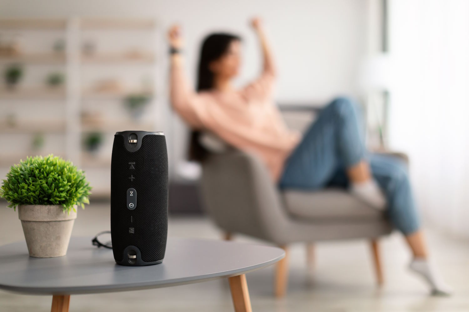 Mujer sentada en un sillón escucha música con un altavoz